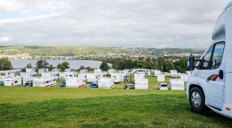 husbilar på rad på campingplats vid sjö